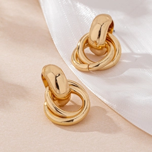 Detailed view of gold geometric intertwined circle earrings on elegant silk background