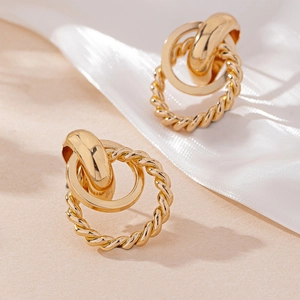 Détail macro de boucles d'oreilles doubles anneaux dorés avec texture torsadée et finition polie