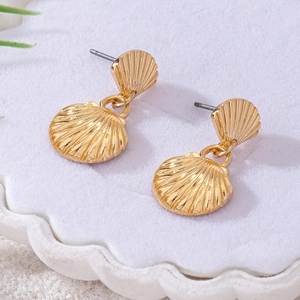 Elegant gold seashell drop earrings featuring textured fan shapes on white sand background