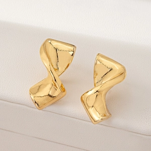 Detailed shot of golden spiral twisted earrings on white leather texture background