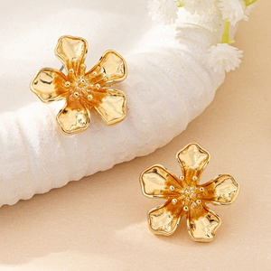 Gros plan de boucles d'oreilles fleurs dorées à cinq pétales aux textures réalistes