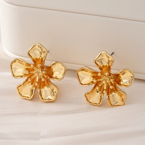 Boucles d'oreilles fleurs dorées avec pétales texturés sur tissu blanc délicat