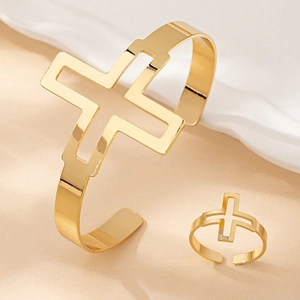 Macro detail of gold cross-shaped adjustable open cuff bracelet and matching ring set