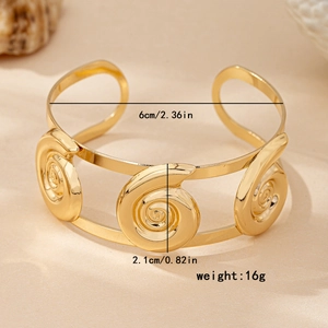 Gold spiral conch open cuff bracelet with double rail design on a warm sand background