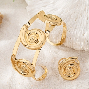 2-piece gold seashell jewelry set with spiral conch bracelet and ring on beach sand