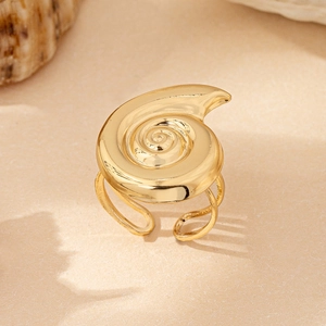 Macro detail of golden spiral seashell ring on a warm sandy background with real shells
