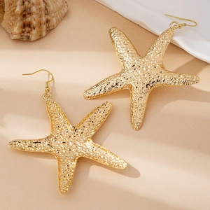Macro detail of gold starfish earrings featuring natural textured finish and hook design