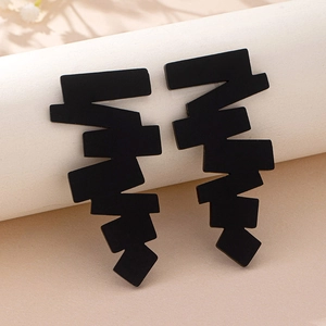 Close-up of matte black irregular geometric zigzag earrings on a white display pedestal