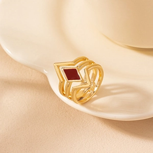 Detailed side view of gold geometric hollow ring with a red enamel diamond-shaped centerpiece