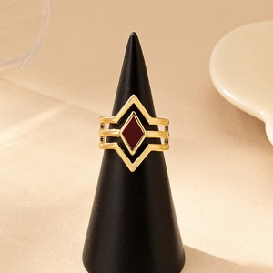 Hollow geometric gold ring with red rhombus enamel on a black display cone stand