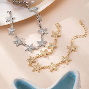 Braccialetti a forma di stella marina in oro e argento su sfondo decorativo marino