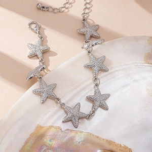 Bracciale con ciondoli a stella marina argentata e texture pavé su sfondo conchiglia