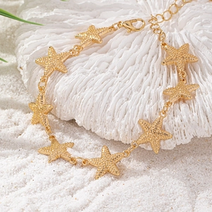 Dettaglio macro del bracciale a stella marina dorata testurizzata su corallo bianco