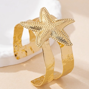 Macro shot of gold starfish open cuff bracelet with hammered texture for beach vacation