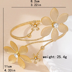 Golden floral upper arm cuff with matte textured petals and sparkling white rhinestones