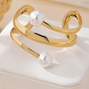 Macro shot of gold spiral open bracelet featuring polished finish and twin white pearls