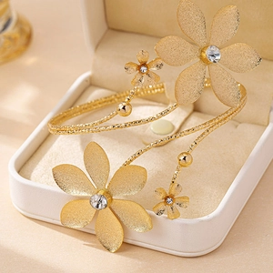 Elegant gold flower arm cuff with matte petals and crystals in a luxury jewelry box