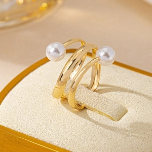 Three-layer spiral open ring in gold with double pearls on a beige jewelry display