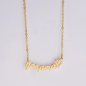 Close-up of a gold necklace featuring a Mama script pendant with a small hollow heart charm
