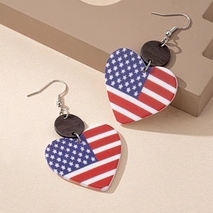 American flag heart earrings with dark wood accent on a textured beige surface