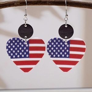 Detail view of American flag heart earrings hanging on a natural wooden branch