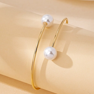 Bracelet jonc ouvert doré minimaliste avec perles blanches élégantes sur un socle