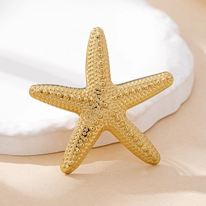 Detailed view of a textured golden starfish ring on a decorative white stone tray