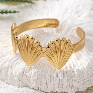 Detailed view of gold scallop seashell open cuff bracelet on white coral stone background