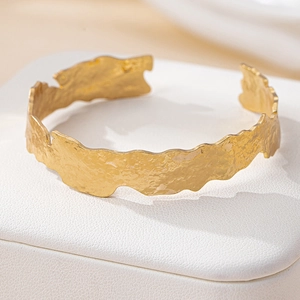 Irregular textured gold bangle with fluid metal ripples and minimalist open design
