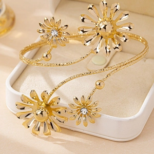 Detailed view of golden daisy arm cuff with rhinestones in a beige jewelry box