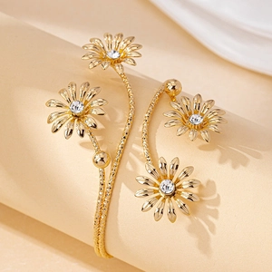 Elegant gold daisy wrap earrings with sparkling rhinestones and hammered texture on beige base