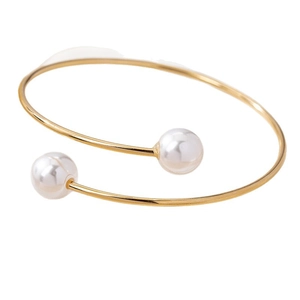 Bracelet jonc ouvert doré minimaliste orné de deux perles blanches sur fond blanc