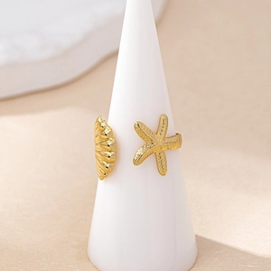Adjustable gold starfish and seashell open ring displayed on a jewelry cone stand