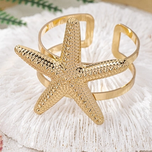 Dettaglio ravvicinato di un bracciale a forma di stella marina dorata su corallo