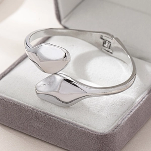 Polished silver minimalist snake-style open cuff bracelet on gray velvet background