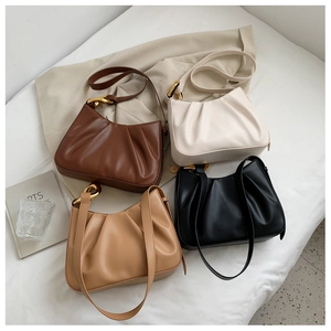 Collection of pleated cloud bucket bags in black, cream and brown with gold chain detail