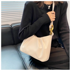 Detail view of off-white pleated bucket bag featuring chunky gold chain hardware
