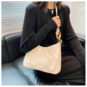Detail of creamy white pleated cloud bag with elegant gold ring hardware on the strap