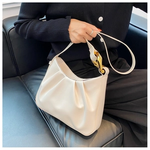 Detail of off-white pleated cloud bag showing luxurious gold chain strap on grey background