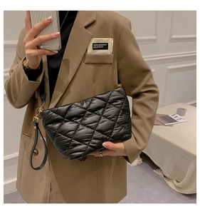 Model wearing a black quilted puffer crossbody bag made of shiny leather and rhombic stitching