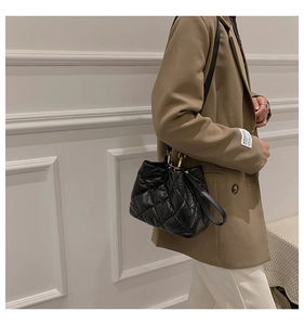 Detail of black quilted bucket bag featuring padded nylon texture and gold metal accents