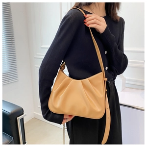 Close-up of khaki pleated bucket bag with adjustable leather strap worn by a model