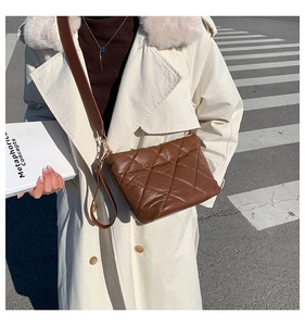 Macro detail of the brown quilted crossbody bag with soft padded diamond stitching texture