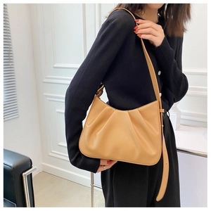 Model wearing a pleated light brown cloud bucket bag showing fit and drape on shoulder