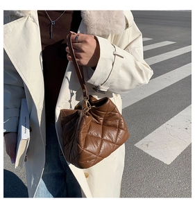 Detail of brown quilted bucket bag with gold hooks and elegant shoulder strap