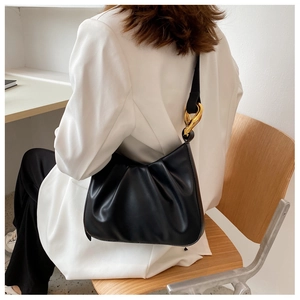 Detailed view of black pleated hobo bag featuring elegant twisted gold metal hardware