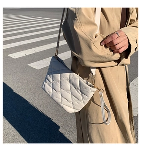 Close-up of white quilted bucket bag with gold hardware and versatile crossbody straps