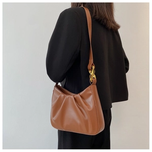 Detail of pleated brown cloud bag showing leather texture and gold chain link buckle