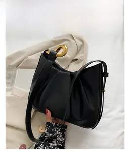Detailed view of black pleated bucket bag with gold horseshoe buckle and strap