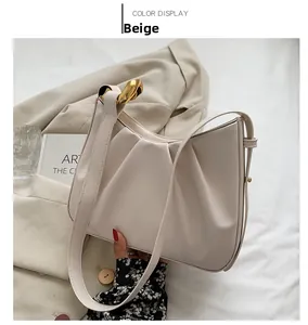 Detail of beige pleated bucket bag with gold chain link and textured faux leather finish